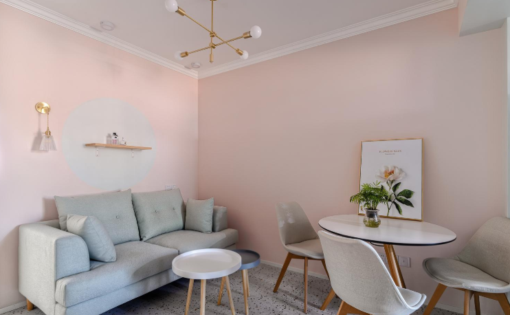 3客厅，客厅的墙面和进门处一样都是粉色的，沙发背景墙上一个木质隔板，一盏壁灯照明，然后就是简单的双人沙发和小茶几，就挺北欧风，.png