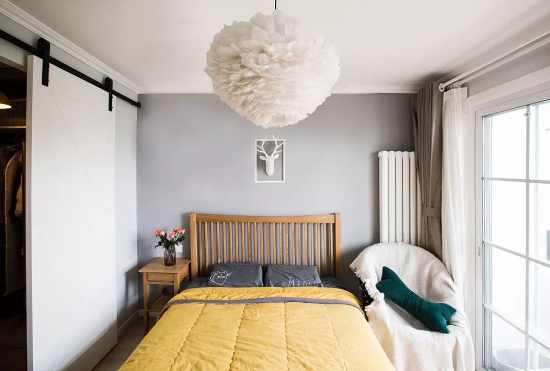 11卧室里床头背景墙是浅灰色的，搭配木质大床，沉稳又有质感，一盏羽毛吊灯柔和整个空间，还提升了卧室的颜值呢。.jpg